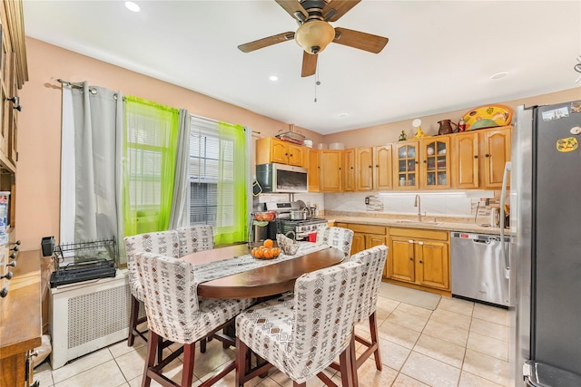 kitchen featuring stainless steel appliances, ceiling fan, sink, radiator heating unit, and light tile patterned flooring