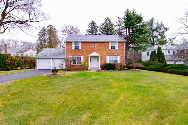 colonial inspired home with a garage and a front lawn