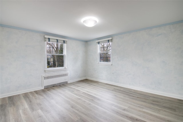 unfurnished room with radiator heating unit, light hardwood / wood-style floors, and ornamental molding