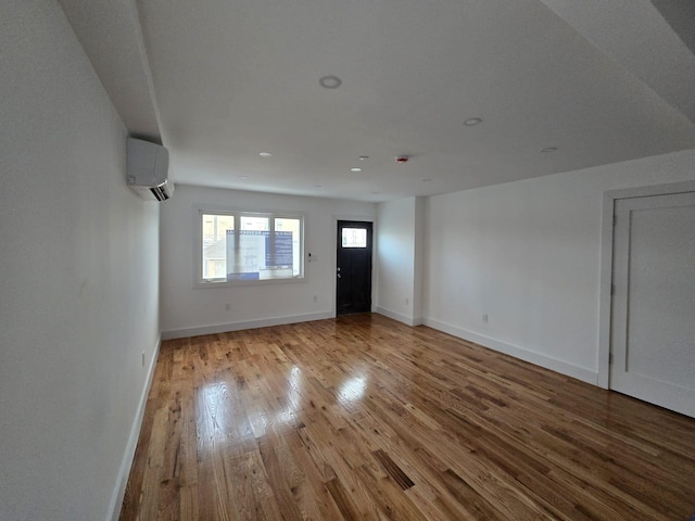 unfurnished living room with a wall unit AC and light hardwood / wood-style flooring