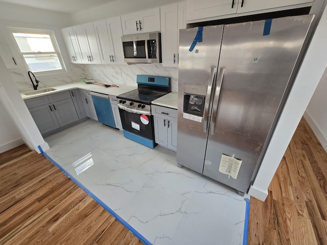 kitchen featuring gray cabinetry, white cabinetry, sink, decorative backsplash, and appliances with stainless steel finishes