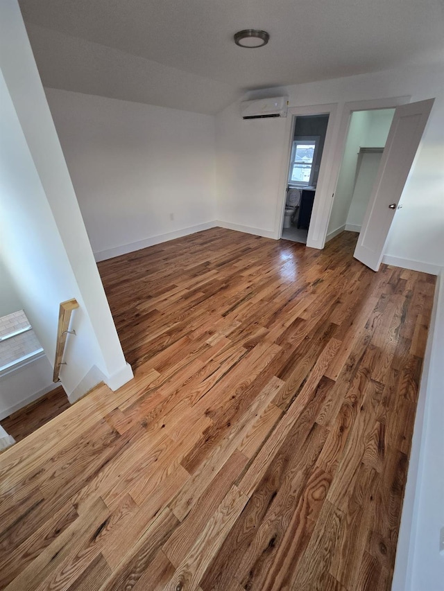 unfurnished room featuring hardwood / wood-style floors and an AC wall unit