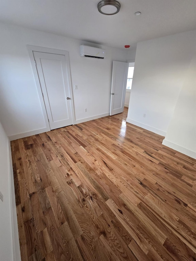 spare room featuring a wall mounted AC and light hardwood / wood-style flooring