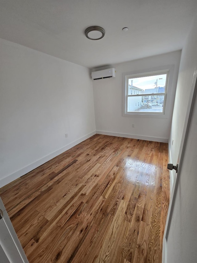 spare room featuring a wall mounted air conditioner and light hardwood / wood-style flooring