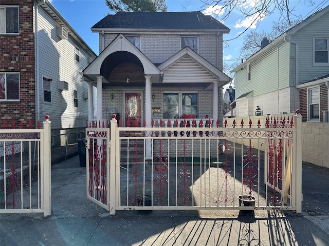 view of front of property with a fenced front yard, a gate, brick siding, and a shingled roof