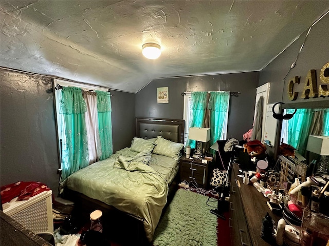 carpeted bedroom featuring lofted ceiling and multiple windows