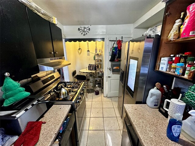 kitchen with stainless steel gas stove, light countertops, dark cabinets, and under cabinet range hood