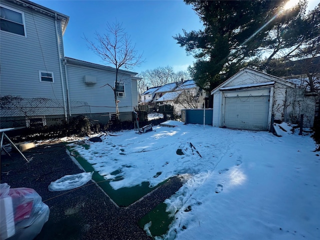 yard layered in snow with a garage, an outbuilding, and fence