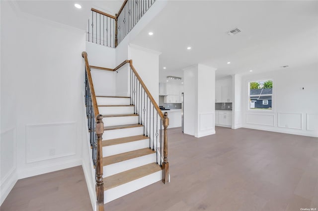 staircase featuring hardwood / wood-style floors and crown molding