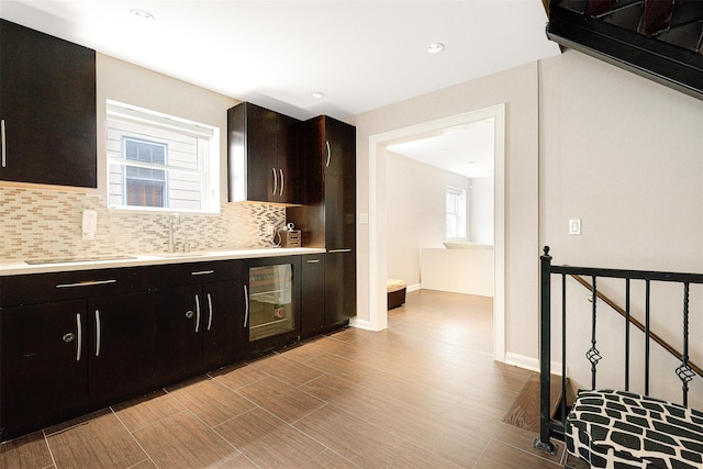 kitchen featuring dark brown cabinets, backsplash, beverage cooler, and sink