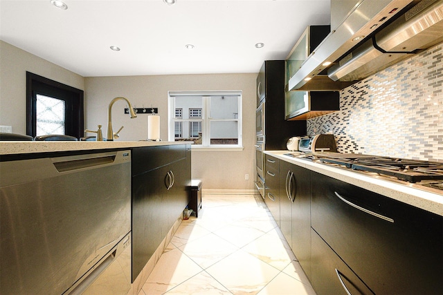 kitchen with sink, stainless steel appliances, wall chimney range hood, backsplash, and light tile patterned floors