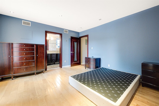 bedroom with ensuite bathroom and light wood-type flooring