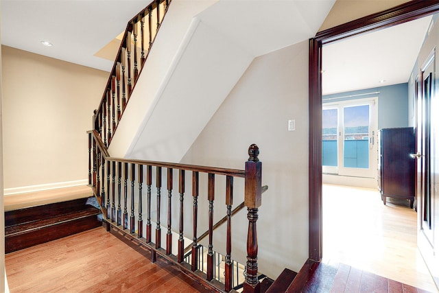 stairway with hardwood / wood-style floors and vaulted ceiling