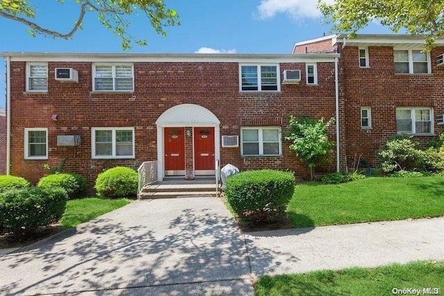 view of front of property with an AC wall unit and a front yard