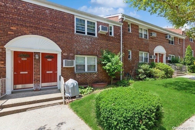 view of front facade featuring a wall mounted AC and a front lawn