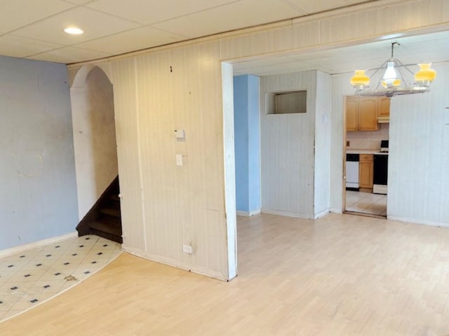 empty room with light wood-type flooring and an inviting chandelier