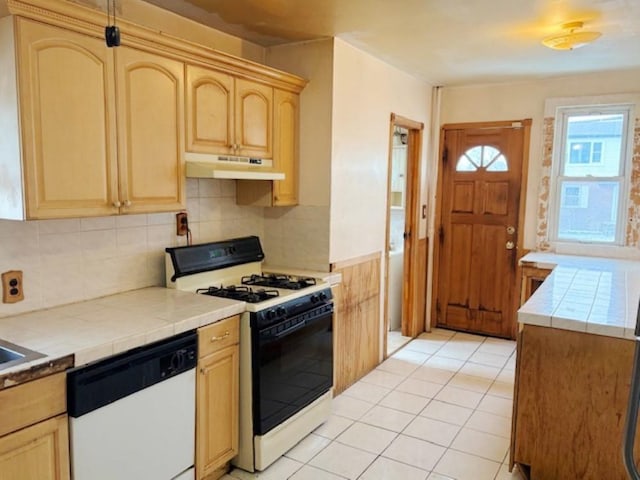 kitchen featuring dishwasher, tile counters, light tile patterned floors, gas stove, and decorative backsplash