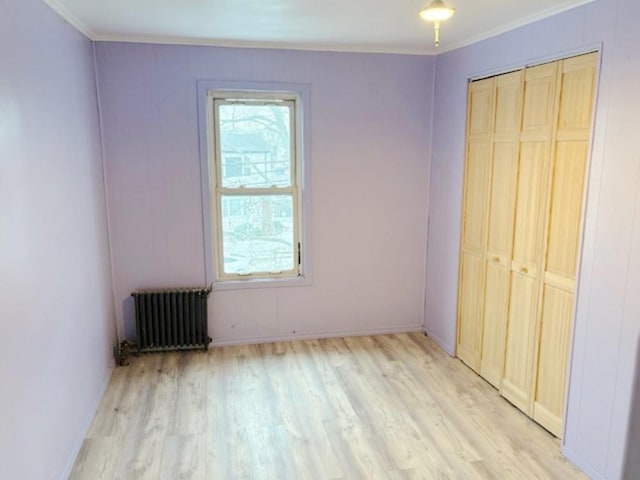 unfurnished bedroom with ornamental molding, light wood-type flooring, a closet, and radiator heating unit