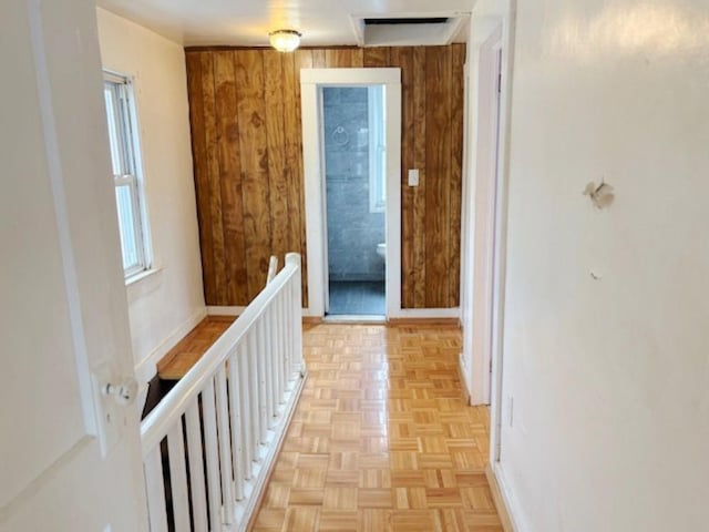 corridor featuring wood walls, a wealth of natural light, and light parquet floors