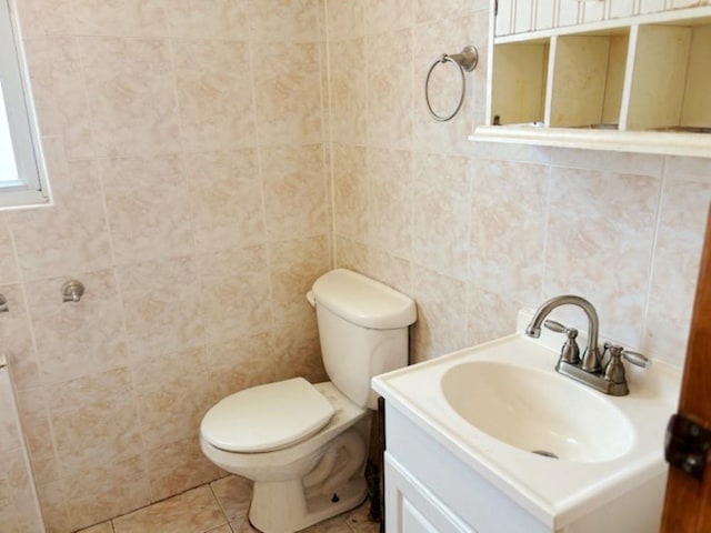 bathroom featuring toilet, vanity, tile patterned floors, and tile walls