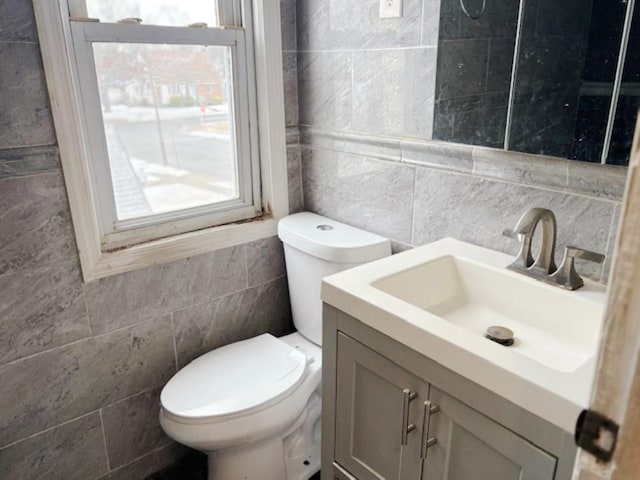 bathroom featuring toilet, vanity, and tile walls