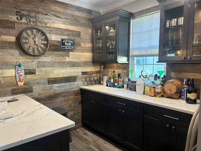 bar featuring light stone countertops, sink, dark hardwood / wood-style flooring, wood walls, and crown molding