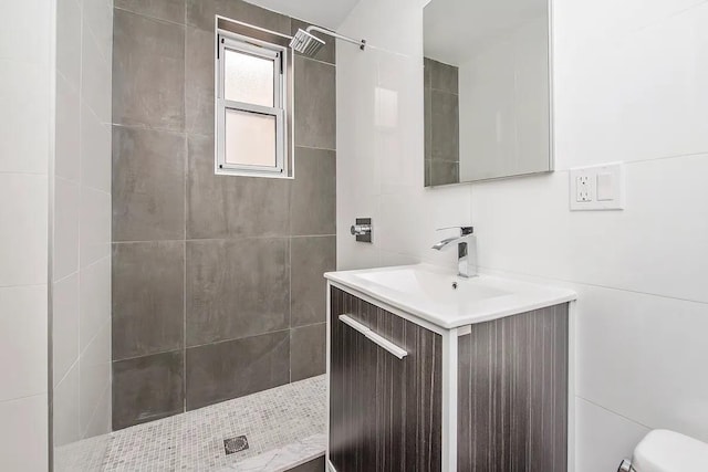 bathroom with vanity, toilet, walk in shower, and tile walls