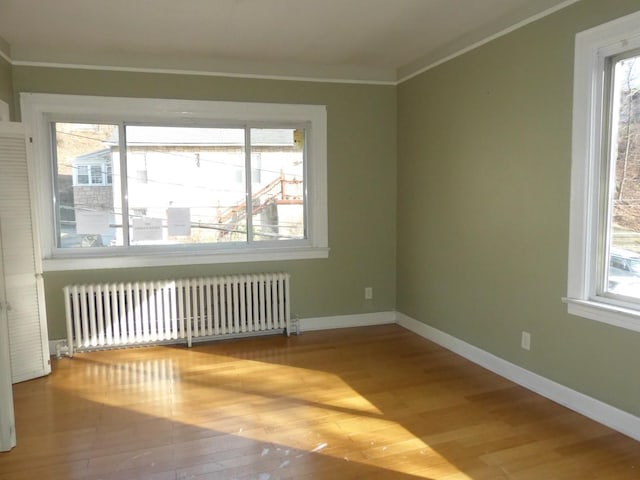 spare room featuring radiator, ornamental molding, and light hardwood / wood-style floors