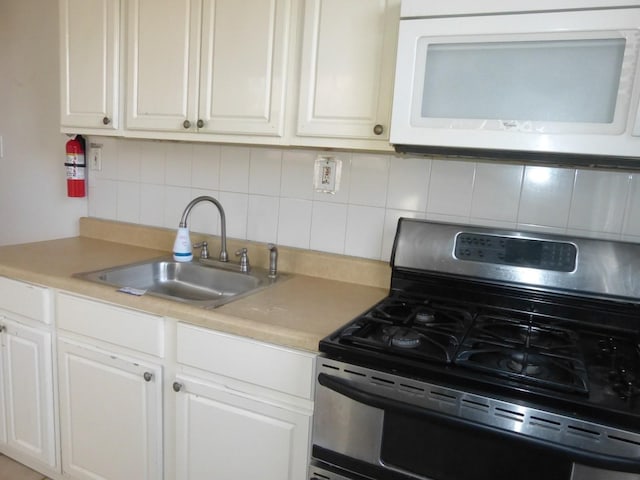 kitchen featuring tasteful backsplash, white cabinets, sink, and stainless steel range with gas cooktop