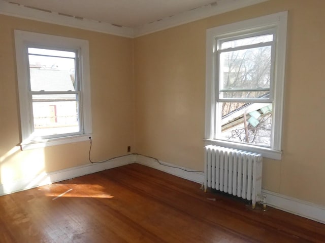 spare room featuring radiator, dark hardwood / wood-style floors, and crown molding