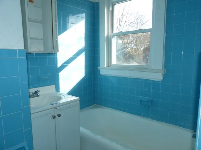 bathroom with tile walls, vanity, and a bathing tub