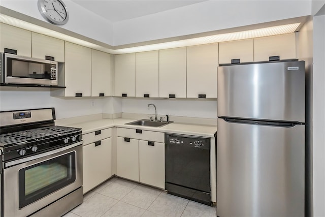 kitchen with sink, light tile patterned floors, stainless steel appliances, and cream cabinets