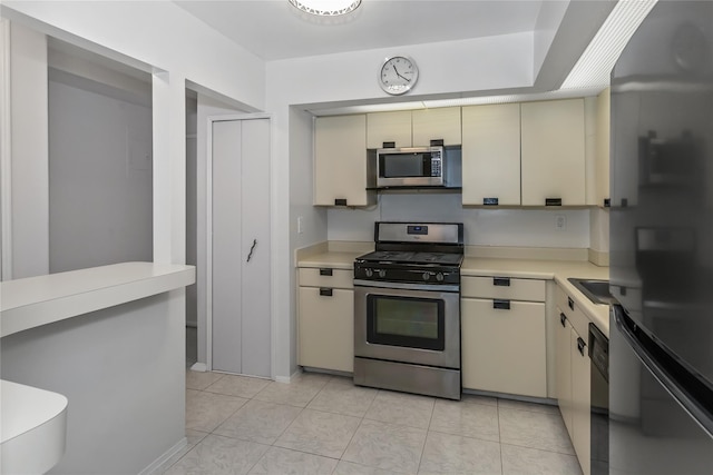 kitchen featuring appliances with stainless steel finishes, light tile patterned floors, and cream cabinets