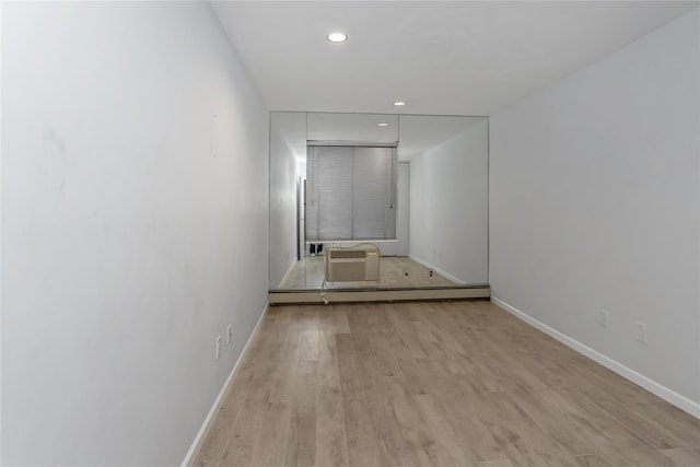 corridor with light hardwood / wood-style floors, a baseboard radiator, and a wall mounted AC