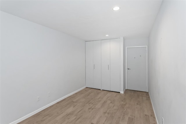 unfurnished bedroom featuring light hardwood / wood-style flooring and a closet