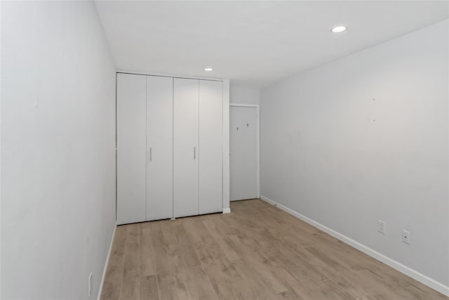 unfurnished bedroom with light wood-type flooring and a closet