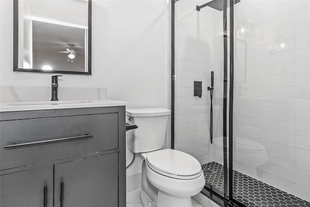 bathroom featuring tiled shower, ceiling fan, vanity, and toilet