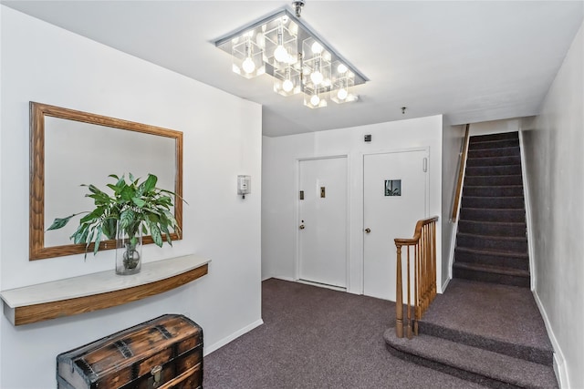 entrance foyer featuring an inviting chandelier and dark carpet