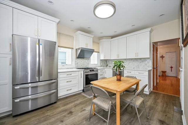 kitchen with white cabinets, ventilation hood, dark wood-type flooring, and appliances with stainless steel finishes