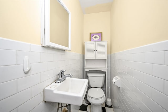 bathroom with sink, tile walls, and toilet