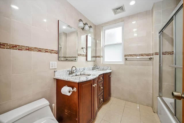 full bathroom with enclosed tub / shower combo, tile patterned floors, toilet, vanity, and tile walls