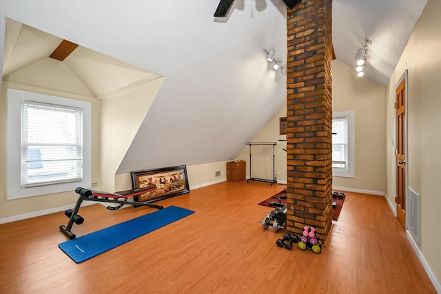 exercise room with plenty of natural light, ornate columns, hardwood / wood-style floors, and lofted ceiling