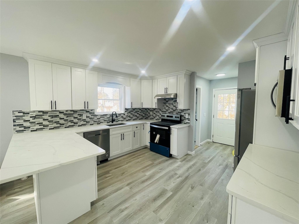 kitchen with appliances with stainless steel finishes, sink, white cabinets, decorative backsplash, and light stone counters