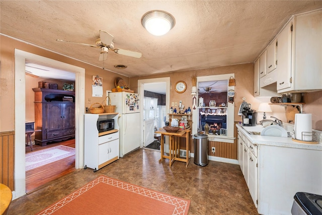 kitchen featuring white cabinets, a textured ceiling, white refrigerator, and sink