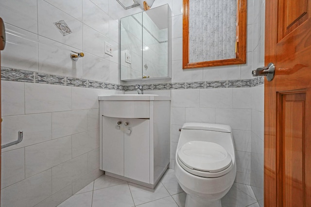 bathroom featuring toilet, tile patterned floors, vanity, and tile walls