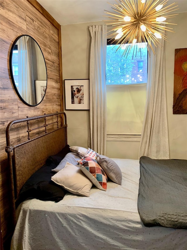 bedroom with wooden walls and a notable chandelier