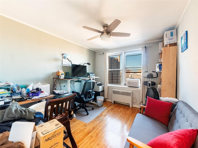 office area featuring radiator heating unit, light wood-type flooring, and ceiling fan