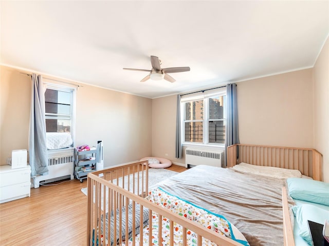 bedroom with ceiling fan, radiator, crown molding, and light hardwood / wood-style floors