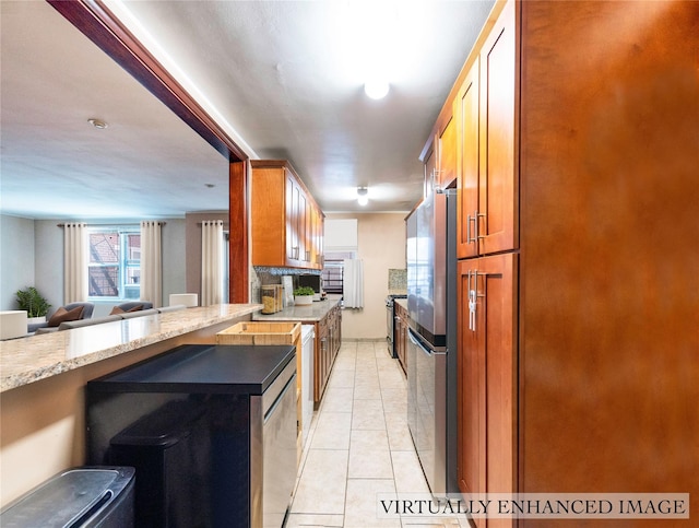 kitchen featuring appliances with stainless steel finishes, light tile patterned floors, and light stone counters