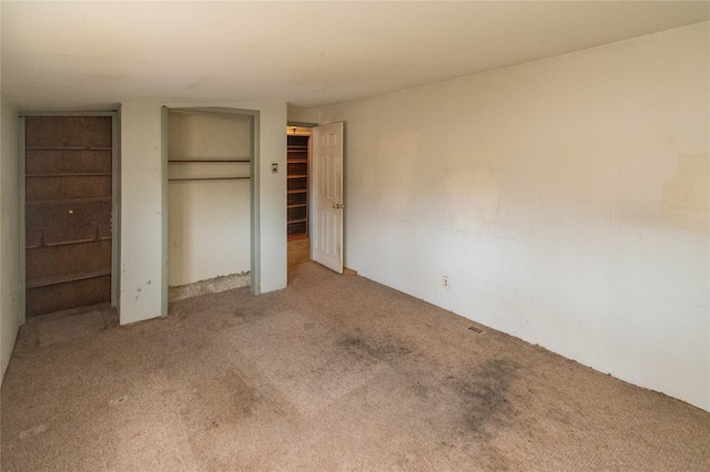 unfurnished bedroom featuring two closets and carpet flooring